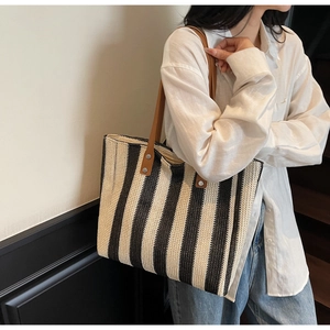 Minimalist straw tote bag with black and white stripes and leather straps on model
