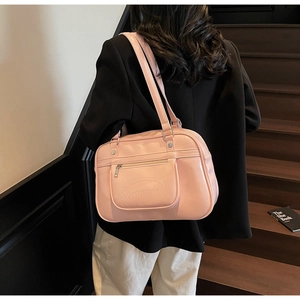 Detailed side view of the pink faux leather shoulder bag worn by a model on stairs