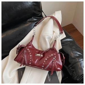 Détail du sac en cuir verni bordeaux avec rivets argentés et bandoulière chaîne