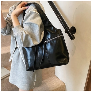 Détail du sac à bandoulière noir brillant avec fermeture éclair et gland long en cuir