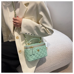 Detalle de bolso saco verde menta acolchado con hebilla de flor dorada y cadena larga