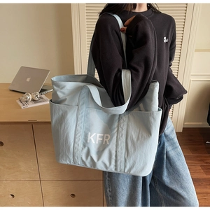 Close-up of light blue canvas tote bag with KFR logo and wide shoulder strap