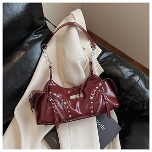 Gros plan du sac en cuir verni bordeaux avec rivets argentés et bandoulière chaîne