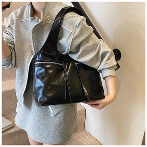 Détail du grand sac cabas en cuir verni noir brillant avec des fermetures éclair décoratives