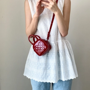 Detail view of heart-shaped red crossbody bag with white polka dot pattern for women