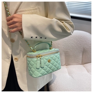 Detalle del bolso caja acolchado verde menta con adorno floral dorado y cadena