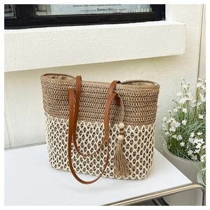 Close-up of woven straw tote bag with brown leather straps and stylish tassel detail