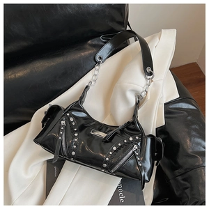 Détail du sac à bandoulière Y2K noir brillant avec clous argentés et zips sur un blazer