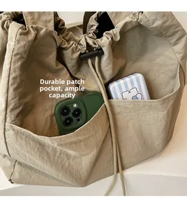 Detail of durable front pocket on khaki nylon tote bag showing spacious capacity