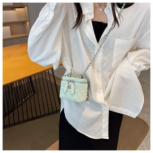 Detail of mint green quilted mini bag with silver chain strap and floral zipper pull