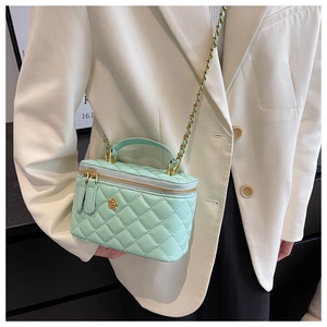 Mint green quilted mini crossbody bag with gold floral logo worn by a model