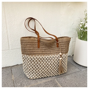 Detailed close-up of woven straw tote bag featuring contrast stitching and leather handles