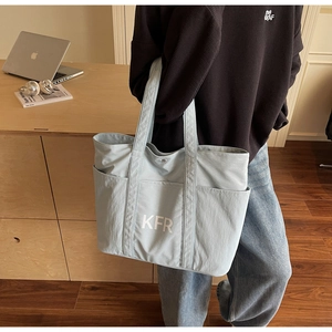 Detail of light blue canvas tote bag with KFR lettering and side pockets for storage