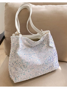 Iridescent sequin tote bag with white leather handles and spacious interior on sofa