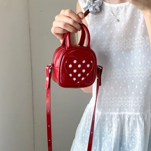 Detail of red PU mini bucket bag featuring a polka dot heart charm and smooth finish