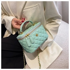 Detail of mint green quilted bucket bag with gold flower charm and chain strap