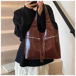 Détail du sac cabas en cuir verni bordeaux avec double fermeture éclair à longs glands