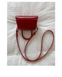 Vista dall'alto del mini sacchetto a trapezio rosso con tracolla su tessuto bianco