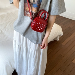 Detail of red PU leather mini crossbody bag with a white polka dot heart decoration