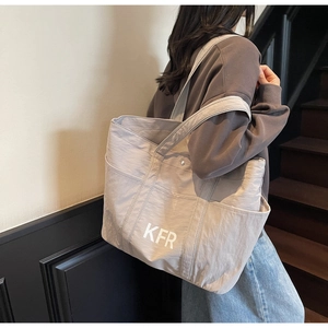 Detail view of a large canvas tote bag with side pockets and a white KFR logo print