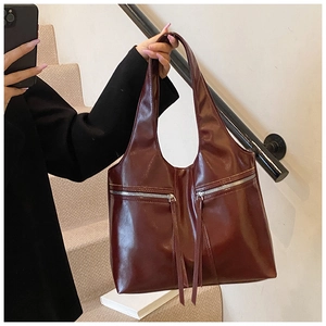 Détail du cabas en cuir verni bordeaux avec zips argentés et longues franges
