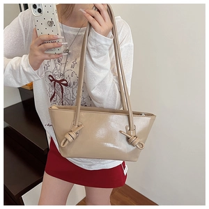 Détail de la texture en cuir PU beige brillant et du design à nœuds sur la bandoulière