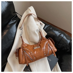 Gros plan des clous argentés et des longs pompons sur un sac à bandoulière marron vintage
