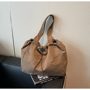 Close-up of brown drawstring tote bag with dual front pockets and textured nylon fabric