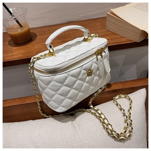 Detalle del bolso caja blanco acolchado con logo de camelia dorada y correa de cadena
