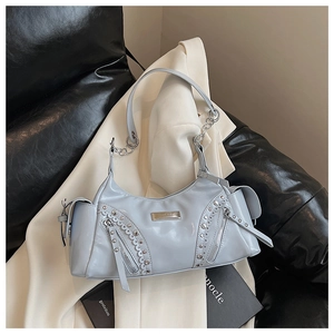 Détail de rivets argentés et fermeture éclair sur sac à bandoulière bleu pastel