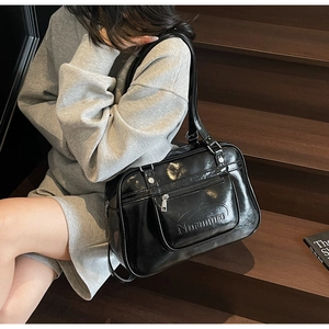 Detail of black glossy shoulder bag featuring embossed lettering and silver hardware zipper