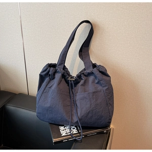 Detail of dark blue nylon tote bag with drawstring closure and wrinkled texture