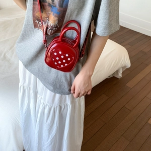 Red heart-shaped mini bag with white polka dots worn by model to show product scale