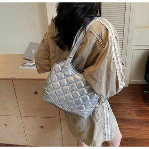 Silberne Stepp-Schultertasche mit Metallstern und Nieten am Arm des Modells getragen