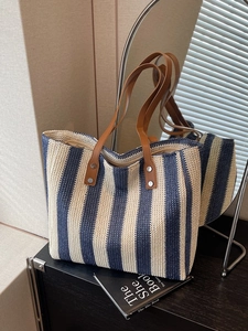 Minimalist navy striped woven tote bag with brown leather handles on dark wood surface