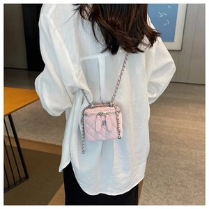 Detail of pink quilted mini crossbody bag with floral zipper pull on a female model