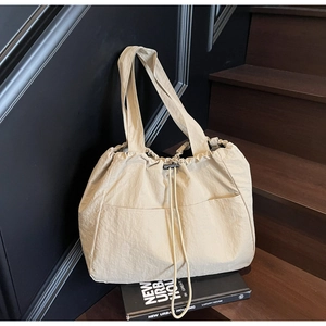 Detail of beige nylon tote bag with drawstring closure on dark stairs