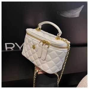 Detalle del mini bolso vanity blanco acolchado con cierre de flor dorada y cadena
