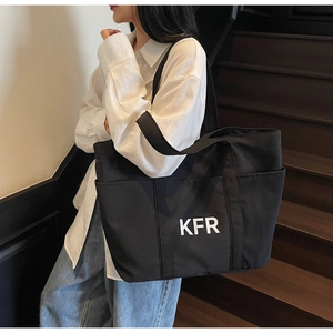 Detail of black large capacity canvas tote bag with white KFR logo on exterior pocket