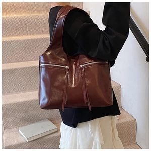 Détail du sac vintage bordeaux montrant la texture du cuir poli et les longues franges zippées
