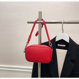 Dettaglio borsa a tracolla rossa in pelle martellata con fibbie metalliche argentate