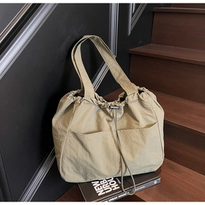 Detail of light khaki nylon tote bag with drawstring closure and two front pockets
