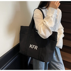 Detail of black canvas tote bag showing KFR logo and functional side pocket