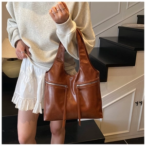 Détail d'un sac cabas marron vintage montrant des fermetures éclair et des pompons