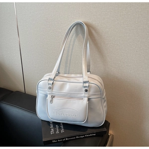 Close-up of light blue patent leather tote bag showing front zip pocket and textured surface