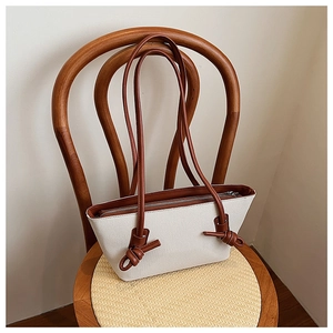 Détail du sac cabas en toile avec des lanières en cuir marron nouées et fermeture éclair