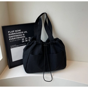 Detail of minimalist black drawstring tote bag with large capacity and double front pockets