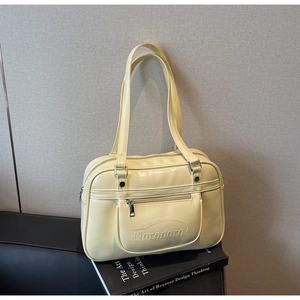 Detail of pale yellow PU leather tote bag with silver zipper pocket and long straps