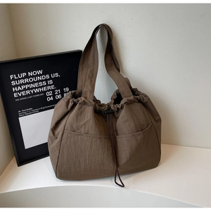 Detail view of the brown drawstring tote bag with dual exterior pockets and textured fabric