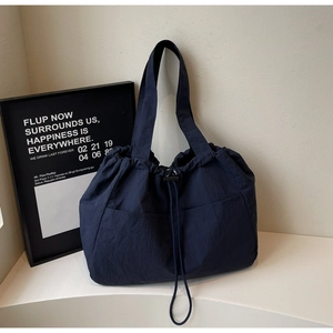 Deep blue nylon tote bag detail with symmetrical pockets and functional drawstring closure